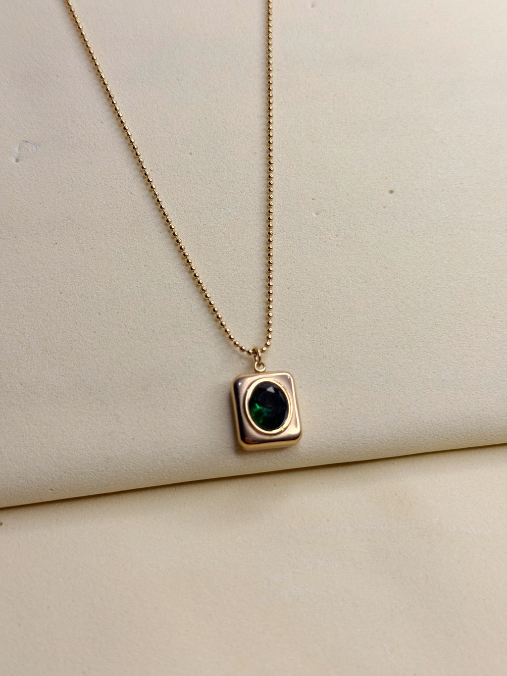 Green Emerald Necklace — emerald-green stone in a gold-toned square setting on a fine ball chain