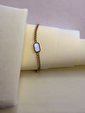 Noir Pearl White Bracelet — black onyx and mother-of-pearl on a fine gold-toned chain, laid on a cream backdrop
